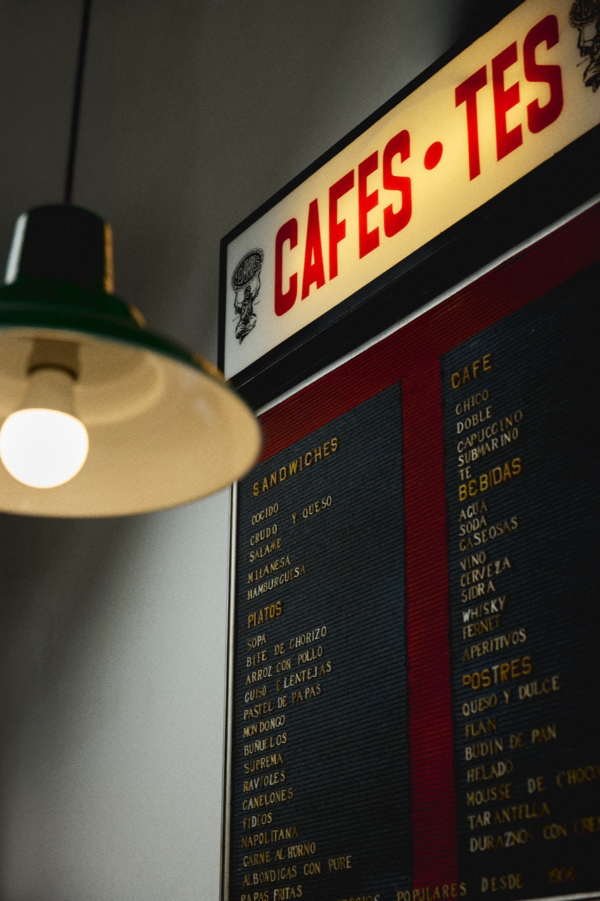 Menu board with red lettering under a green lamp