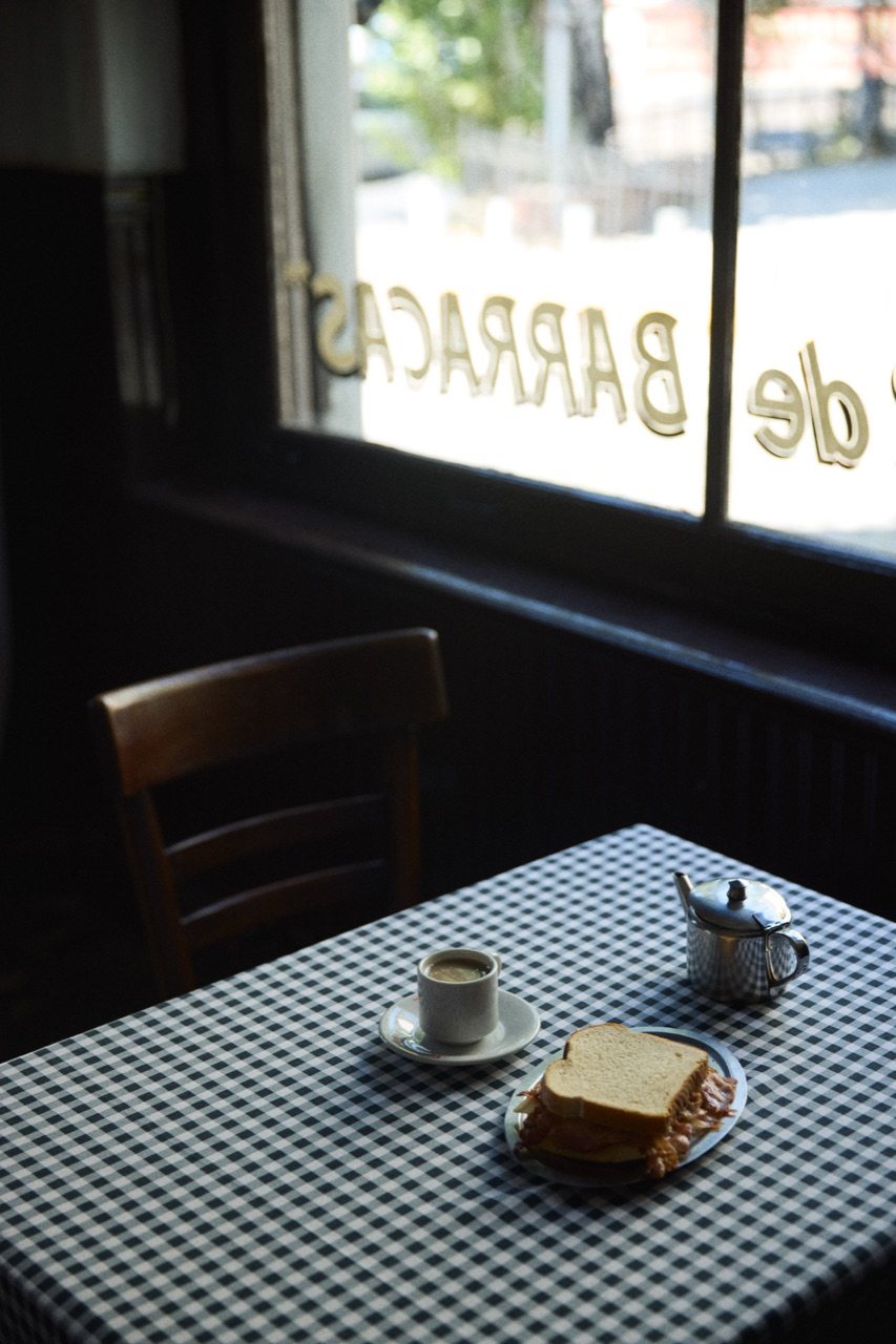 Coffee and a sandwich on gingham by a dark café window