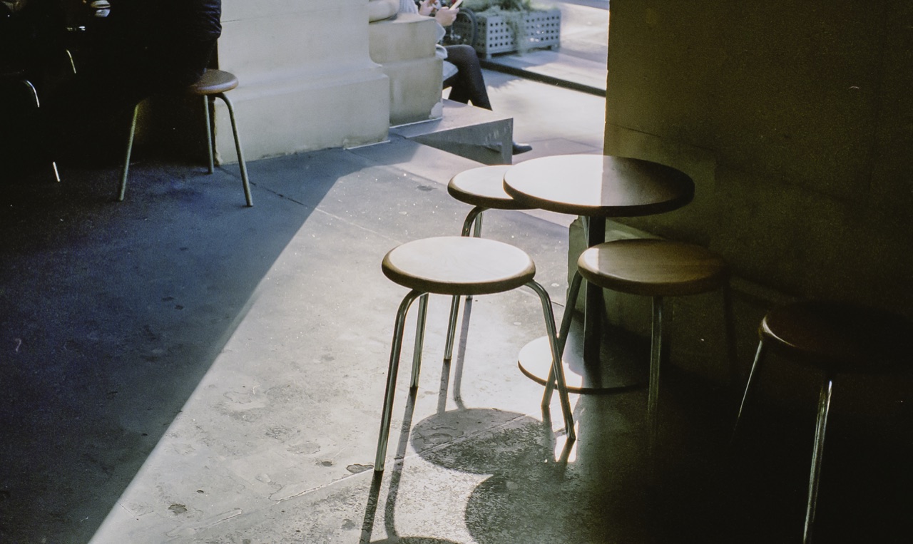 Stools and small tables in a shaded arcade