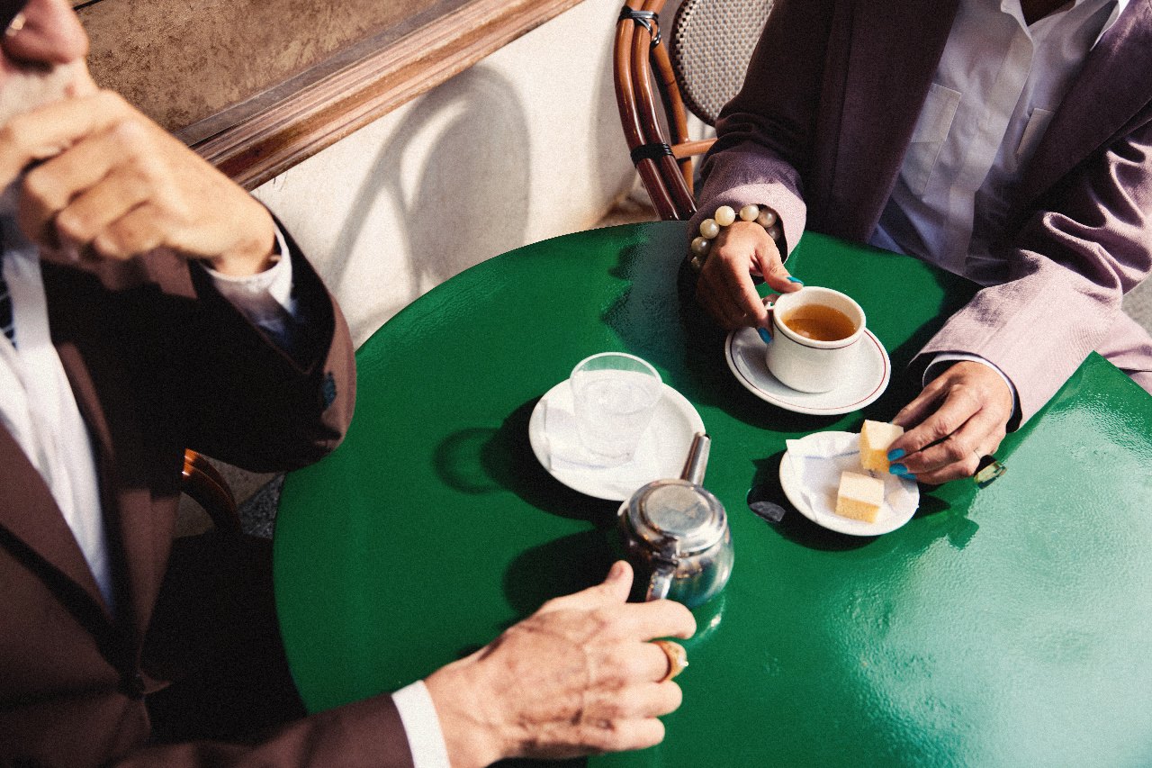 Hands around coffee cups on a green café table
